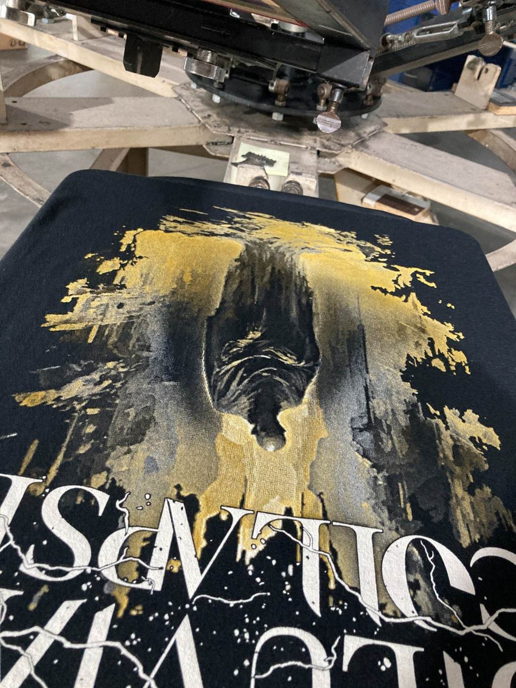 Gold and white custom metal band T-shirt on the screen printing press