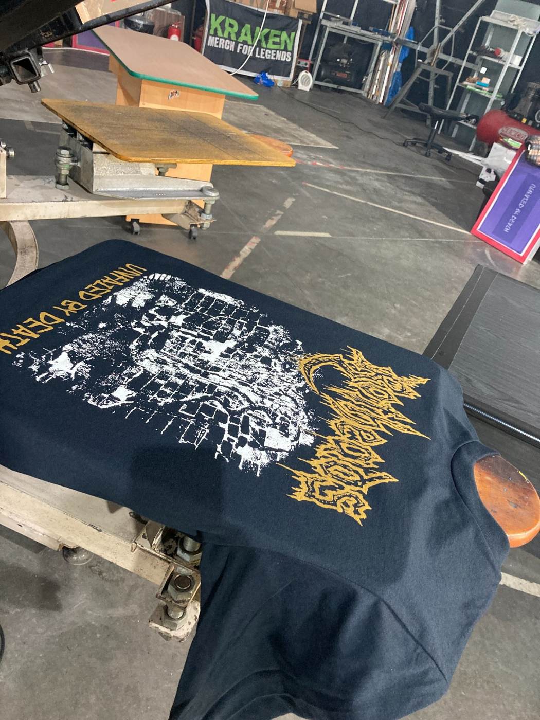 Freshly printed black metal band T-shirt on the screen printing press